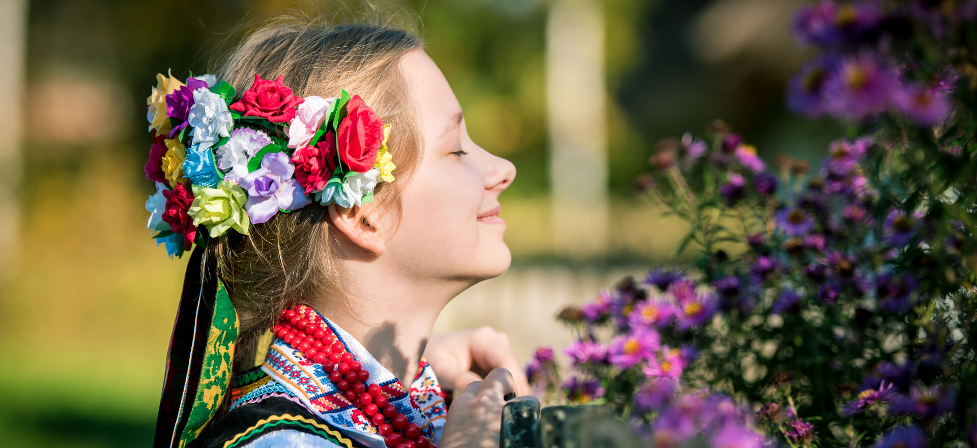 dziewczynka w stroju folkowym wąchająca kwiaty